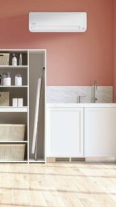 Modern kitchen corner with white cabinets, marble backsplash, and coral wall; wall AC unit above.